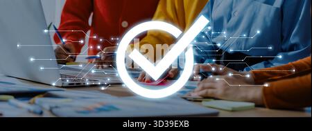 Members of a business team collaborate in a bright workspace. A digital check mark signifies success and approval in their project efforts, showcasing Stock Photo