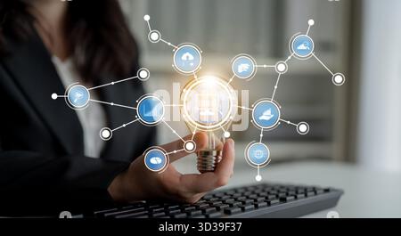 A businessperson holds a glowing light bulb symbolizing innovation while surrounded by technology icons that represent data analysis and creative Stock Photo