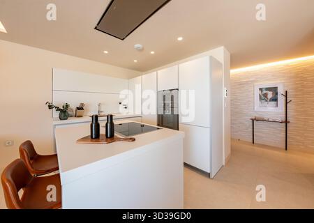 Modern White Kitchen with Island and Bar Stools in luxury mediterranean home Stock Photo