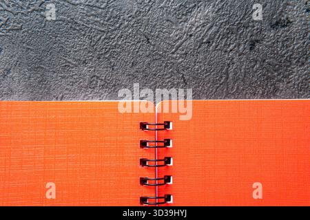Orange Spiral Notebook on a Dark Gray Textured Background Stock Photo