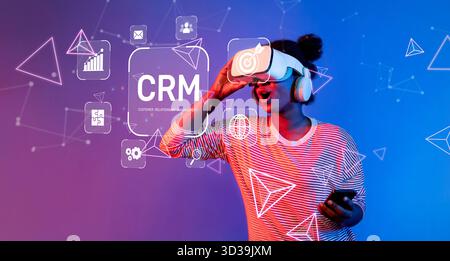 A modern woman experiencing immersive virtual reality while interacting with customer relationship management tools and digital visuals in a vibrant Stock Photo