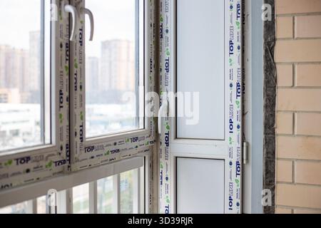 New TOP LINE PVC windows in a room under construction, with a blurred cityscape visible through the glass. Finishing work in a room in a new building. Stock Photo