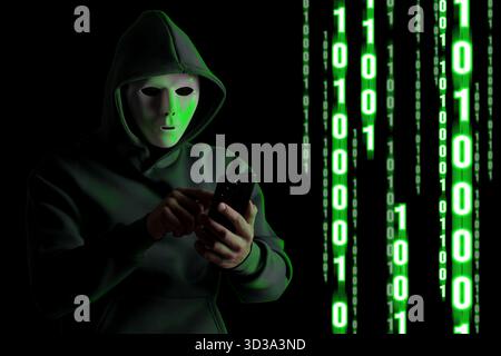 Cyber attack. Hacker in mask using mobile phone on black background. Green glowing binary code near him Stock Photo