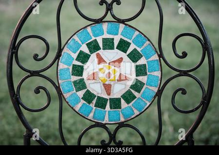Colorful decorative mosaic pattern made of glass and ceramic tiles on wrought iron structure. Stock Photo