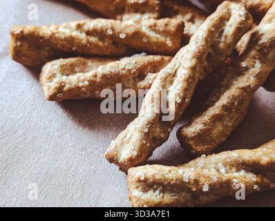 close-up of golden salty grissini breadsticks on a brown craft paper background with large copy space Stock Photo
