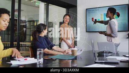 Four businesswomen discussing online sales charts on screen in meeting room, with laptop and charts Stock Photo