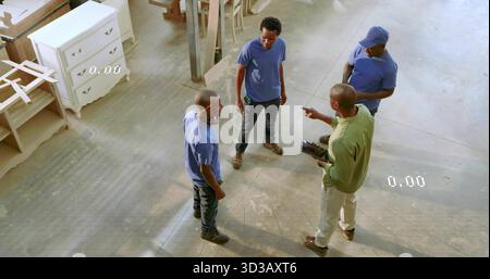 Discussing plans carpentry crew holding tablet and wearing boots in carpentry shop, with planks Stock Photo