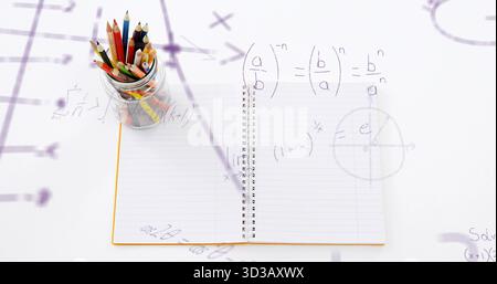 Showing open spiral notebook on white desk, with glass jar holding colored pencils, math overlays Stock Photo