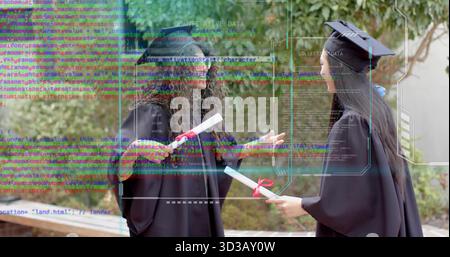 Standing teen graduates wearing black cap-and-gown attire on walkway, holding red-ribboned diplomas Stock Photo