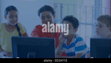 Female instructor guiding three schoolchildren in computer lab classroom, with desktop computers Stock Photo
