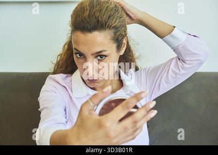 Aging process, mature woman examining her face and skin with small mirror, handglass, hand mirror, hairstyle, makeup, cosmetics, Turkish ethnicity, se Stock Photo