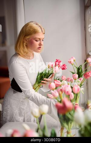 Reflective artist methodically prepares flowers in gentle Stock Photo