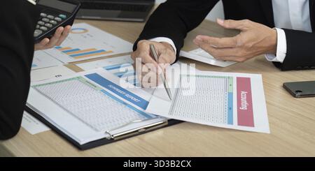 Colleagues analyzing financial documents and summary reports during a business meeting. Focus on collaboration and data-driven decisions Stock Photo