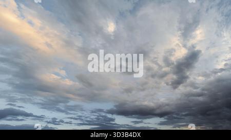 Evening sky with dramatic clouds in various shades and textures. A large panorama of the sky with beautiful clouds illuminated by soft sunlight Stock Photo