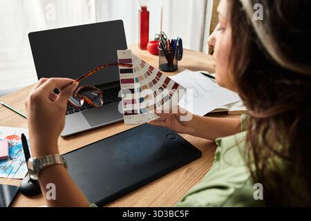 In a cozy apartment, a woman examines a color palette while planning her creative project. Stock Photo