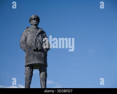 Plymouth, UK  - Sep 25 2025: Bronze figure of a sailor with binoculars on the Merchant Navy and fishing fleet memorial in Plymouth, UK, set against a clear blue sky. Stock Photo