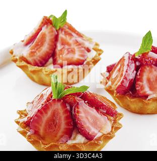 Food, Tartlets with custard, strawberries and mint served on white plate Stock Photo