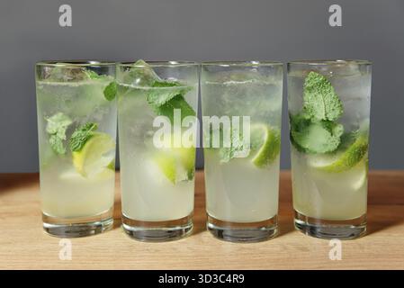 Food, Vibrant glasses of refreshing Mojito drinks, adorned with lime wedges, ice cubes, and fresh mint leaves. Ideal for lively gatherings and festive Stock Photo