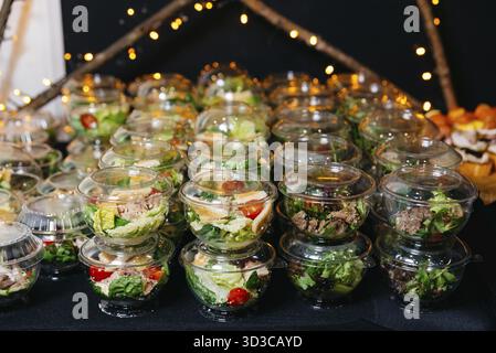 Food, Many portions of various salads with meat and vegetables in plastic serving dishes with lids. Catering serving portions of salads on the table. Stock Photo