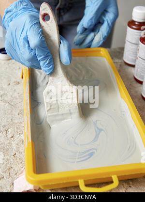 Cropped view of hand wearing gloves using paintbrush and paint Stock Photo