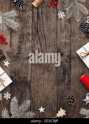 Christmas flat lay wooden background with natural pine branches, red berries, stars, cones and gift boxes, copy space for text or design Stock Photo