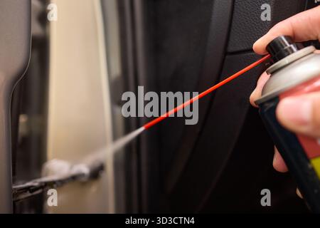 Applying spray lubricant to car door hinges helps keep them functioning