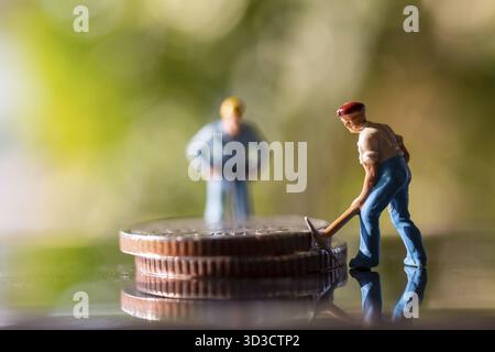 Miniature people worker holding tool on coins with green bokeh background, Construction concept Stock Photo
