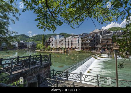 Feng Huang, China - August 2019 : Long time exposure of the small artificial cascade waterfall on the Tuo Jiang riverin the Old Town of Fenghuang know Stock Photo