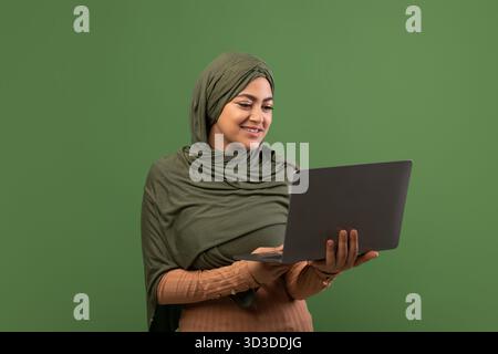 Freelance Online Education for Muslim Women With a Happy Woman in Hijab Using Her Laptop Stock Photo