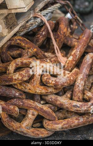 Pile of old, large and heavy rusty chain links in a marina landing in fishing port Stock Photo
