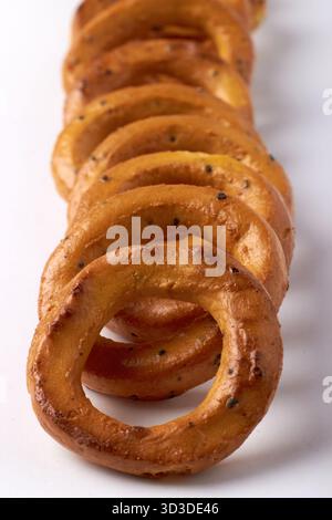 Salted pretzels with poppy seeds lined up in a row isolated on white background, front view. Stock Photo