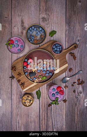 A white ceramic bowl overflowing with golden cereal awaits beside a deep purple smoothie, ready for breakfast. Stock Photo