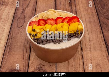 The creamy texture of natural yogurt serves as the base for a rainbow of seasonal fruits, nut toast, and dark chocolate chips. Stock Photo