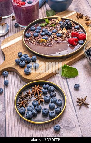 A delicate swirl of yogurt intertwines with the smoothie's deep purple, creating a marbled effect that contrasts with the scattered crunchy cereal Stock Photo