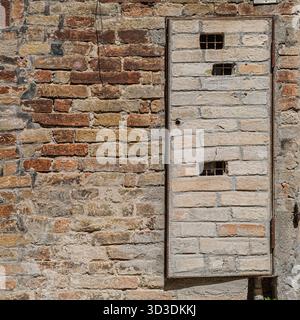 Camouflage: The door of a small utility room must blend in with the surrounding brick wall. Urbino, Marche, Italy Stock Photo