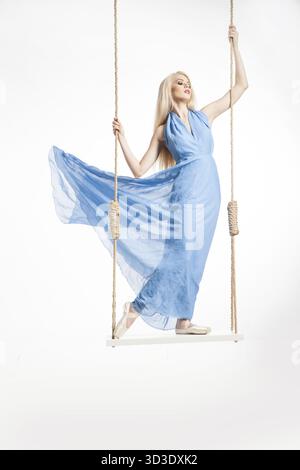 Portrait of beautiful young ballerina standing on swings in blue dress and pointes.Isolated Stock Photo
