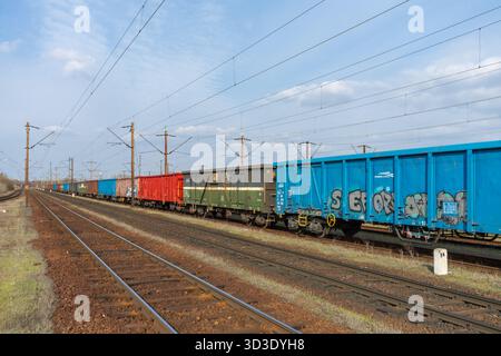 Long line of freight wagons on Budapest marshalling yard mainline (Rákosrendező), showing varied rolling stock, graffiti and rail-yard infrastructure. Stock Photo