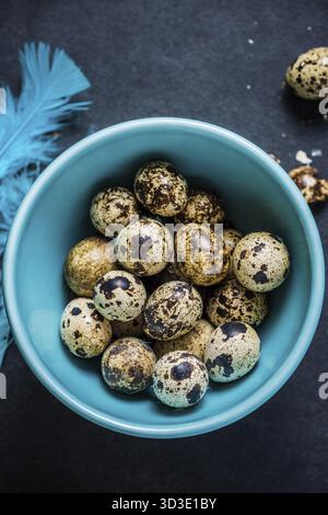 Quail eggs in pastel bowl on dark background, Easter decoration concept Stock Photo