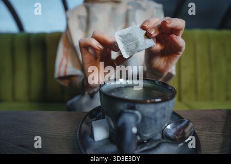 Woman brewing a fresh mug of tea with teabag in a cafe Stock Photo
