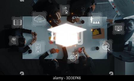 A team of professionals engaged in a strategic meeting around a conference table, with technology and education symbolism enhancing the collaborative Stock Photo
