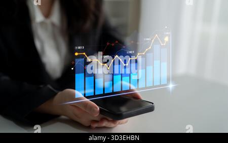 A business professional engages with a smartphone displaying dynamic financial charts and graphs, reflecting modern data analysis trends in a Stock Photo