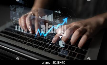 A business professional engages with financial data on a laptop, displaying digital graphs and charts that signify growth and analysis in a Stock Photo