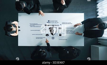 Professionals in suits engage in a serious discussion about cybersecurity strategies, analyzing digital data visualizations at a modern office table Stock Photo