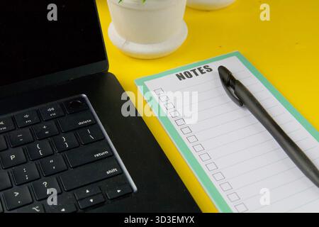 Morning workspace with takeaway coffee cup.Hand holding a takeaway coffee cup near laptop and notepad with pen on a bright desk. Stock Photo