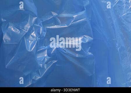 Abstract blue plastic background with crumpled and wrinkled texture. This shiny sheet surface provides detailed and interesting pattern for various de Stock Photo