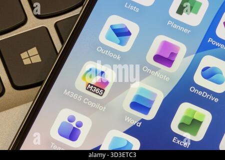 Microsoft 365 apps, including M365 Copilot, Word, Excel, Teams, Outlook, OneNote, OneDrive, and Planner, are seen on the screen of an iPhone. Stock Photo
