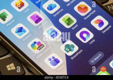 Microsoft 365 apps on an iPhone - M365 Copilot, Word, Excel, PowerPoint, Outlook, OneNote, OneDrive, Planner, Teams, SharePoint, Loop, and Designer. Stock Photo