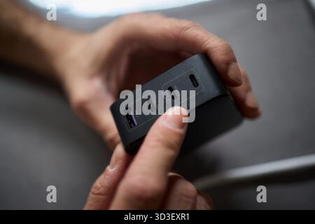 Detailed closeup image of a hand firmly holding a USB hub that features multiple ports Stock Photo