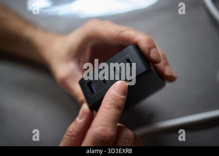 Detailed closeup image of a hand firmly holding a USB hub that features multiple ports Stock Photo