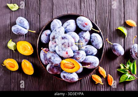 Fresh plums on plate over wooden background Stock Photo